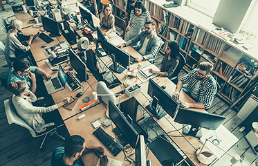 Vergrößerungsansichten für Bild: In einem Büro: Blick auf Männer und Frauen an Computern